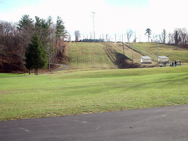 The golf course snakes around the ski hill with holes at the base and top of the slope, and golfers can be seen in the foreground of this photo.  At the top of the hill, horseback riding tours are moving across the summit.